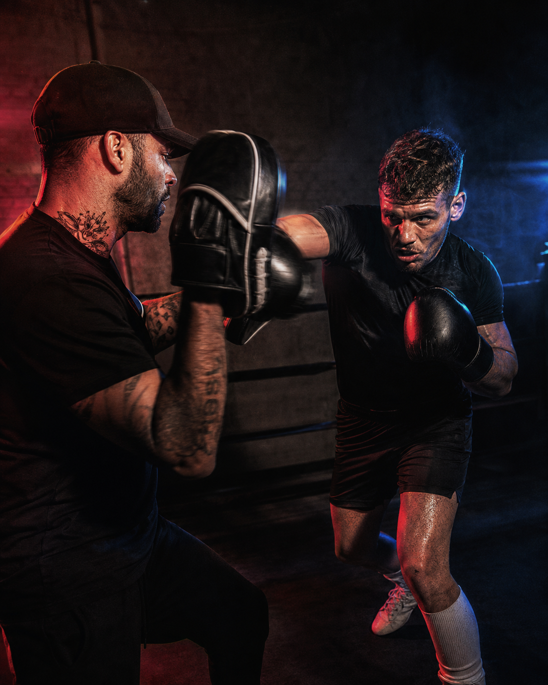 Coach holding pads while a boxer trains